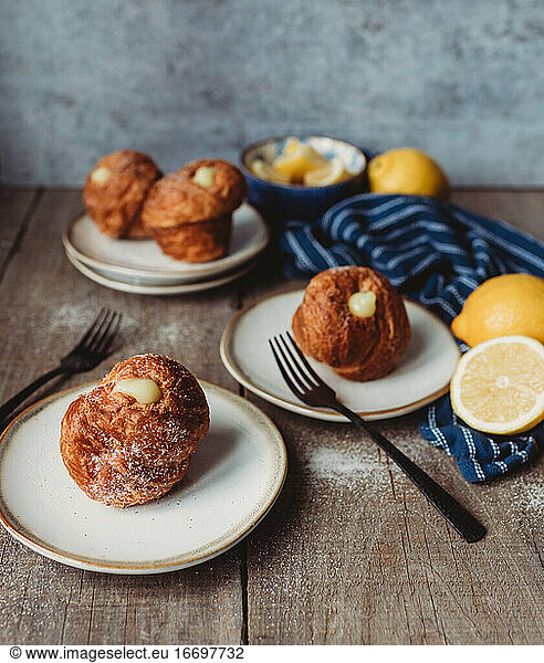 Lemon filled cruffins on wooden table with plates and forks.