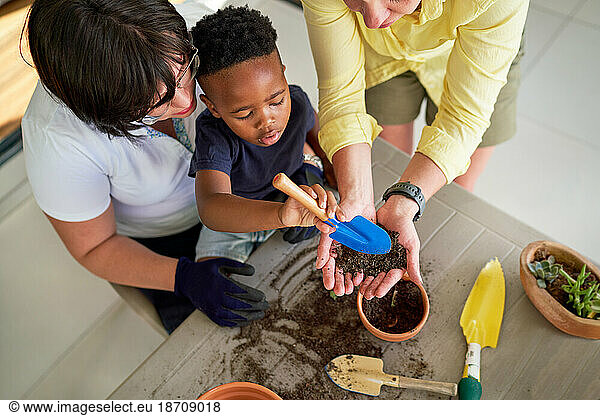 Lesbian couple and son digging in dirt  planting in flowerpots