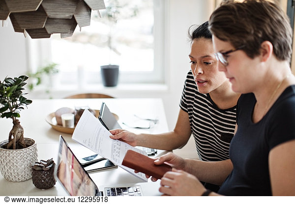 Lesbian couple discussing over financial bills while using laptop at table