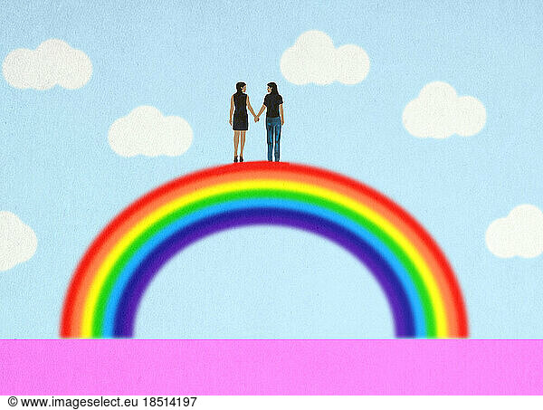 Lesbian couple holding hands on top of rainbow