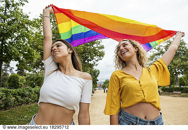 Lesbian couple holding rainbow flag in park