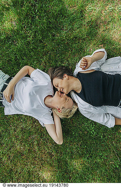 Lesbian couple kissing lying on grass