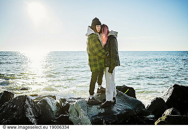 Lesbian couple standing together on rocks near sea