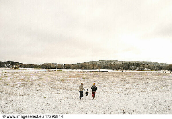 Lesbian mothers and daughter running on snow covered land