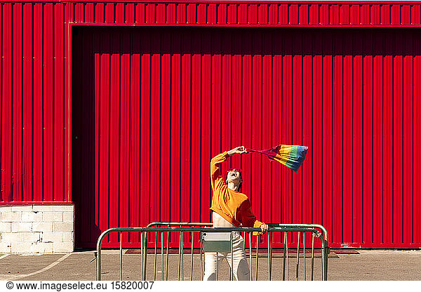 Lesbian with colorful bag and a barrier in front of a red wall
