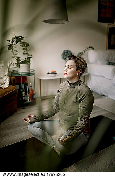 Lesbian woman with eyes closed practicing yoga at home