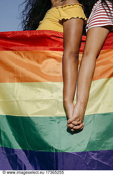 Lesbian women with rainbow flag holding hands