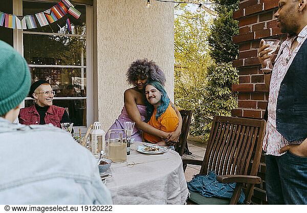 LGBTQ friends embracing each other during dinner party in back yard