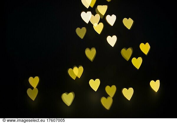 Lichteffekt mit gelben Herzen vor schwarzem Hintergrund  Bokeh