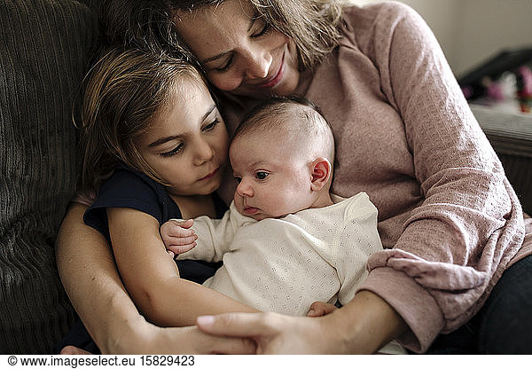 Liebende Mutter umarmt 4 Jahre alte Tochter und Neugeborenes
