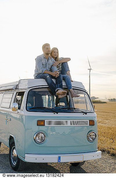 Liebenswertes junges Paar auf dem Dach eines Wohnmobils in ländlicher Landschaft