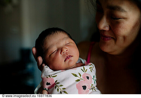 Liebevolle asiatische Mutter bewundert neugeborenes Baby