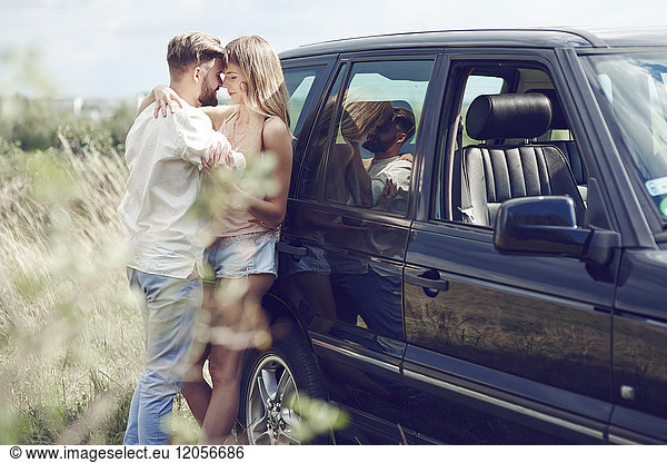 Liebevolles junges Paar außerhalb des Autos