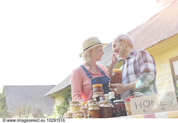 Liebevolles Seniorenpaar  das Honig auf dem Bauernmarkt verkauft.
