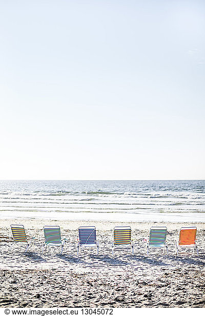 Liegestühle auf Sand am Strand angeordnet