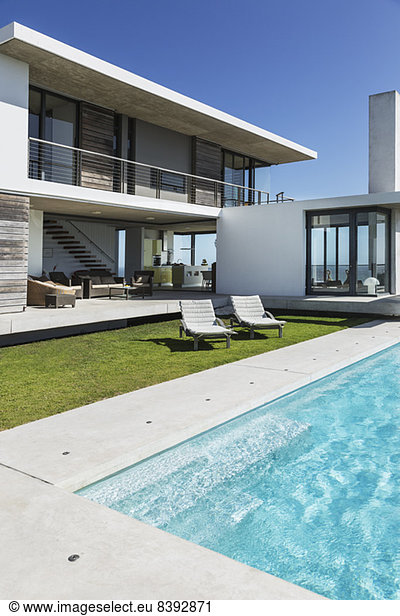 Liegestühle und Schwimmbad vor dem modernen Haus