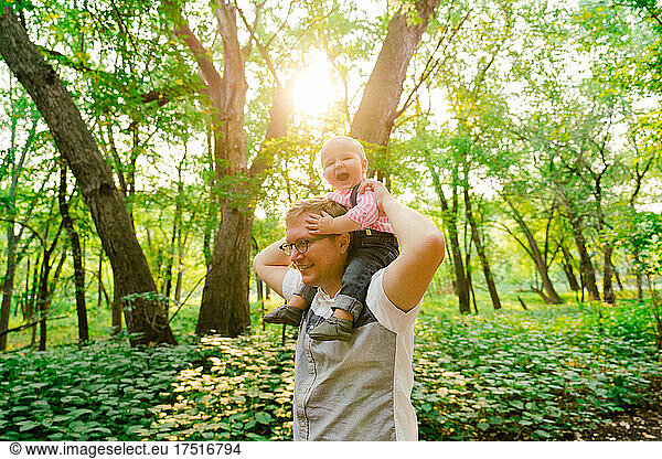 Lifestyle portrait of a baby riding on his dad's shoulders