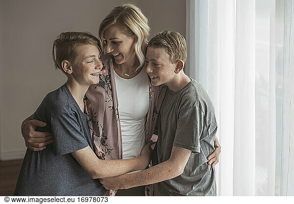 Lifestyle portrait of beautiful mother and two teen boys in studio