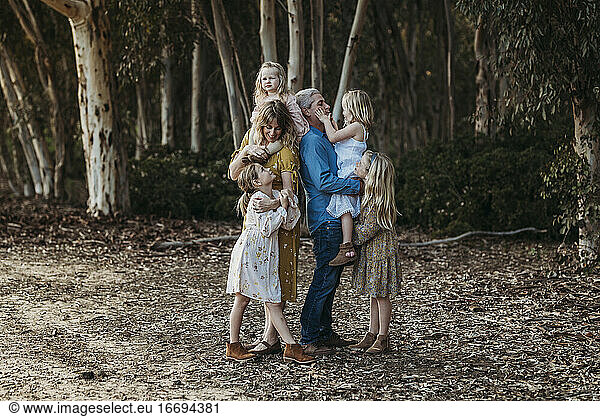 Lifestyle Portrait of Young Family Hugging Outside