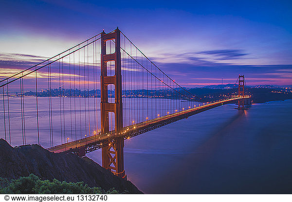 Light trails on Golden Gate Bridge against blue sky at dusk