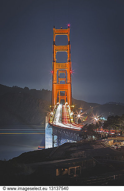 Light trails on Golden Gate Bridge against sky at dusk