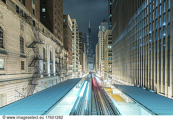 Light trails on railroad tracks amidst buildings in city at night  Chicago  USA