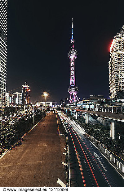 Light trails on road against Illuminated Oriental Pearl Tower in city at night