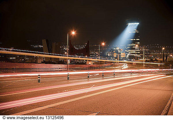 Light trails on road in illuminated city at night