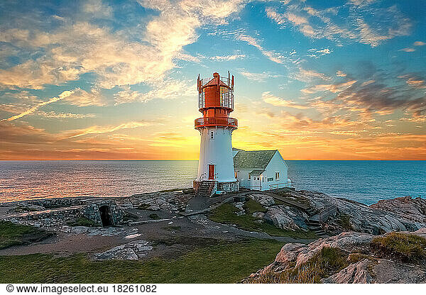 lighthouse surrounded by rocks at sunset