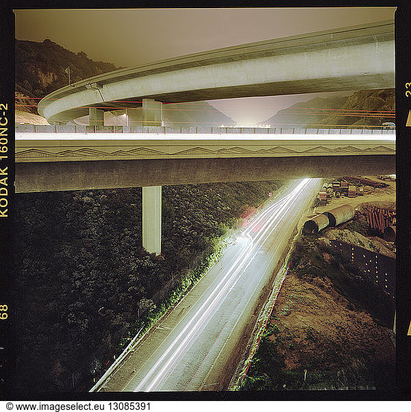 Lights trails on overpass by mountain during sunset