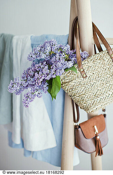 Lilac flower in handbag hanging on clothes rack