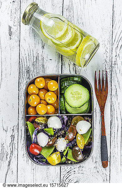 Limonadenflasche und Lunchbox mit Gurkenscheiben  Winterkirschen und Quinoa-Salat (Quinoa  Kirschtomate  Rotkohl  Zuckerschoten und Mozzarellakugeln)