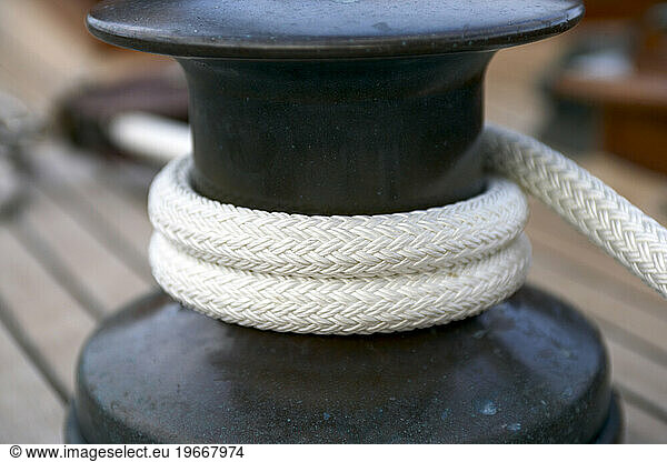 Line wraped around a winch on the deck of a sailing yacht.