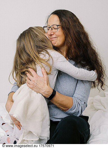 litte toddler girl happily hugging her grandmother