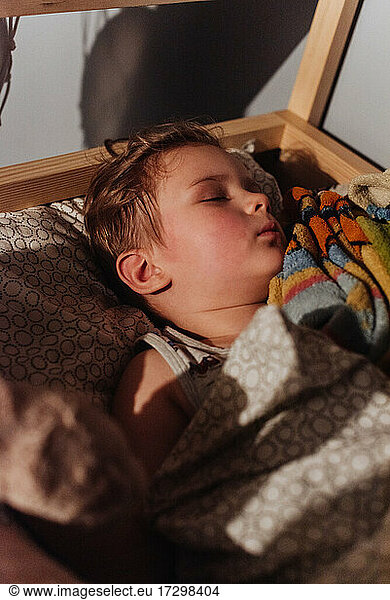 Little blond boy sleeping in his bed