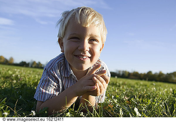 Little boy (2-3 years) lying in the meadow,  smiling,  portrait