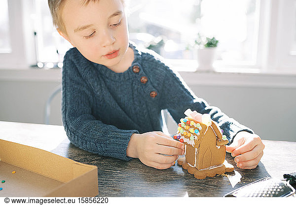 Little boy building a gingerbread house.