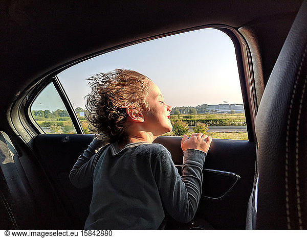 Little boy enjoying the wind in his hair while in the car