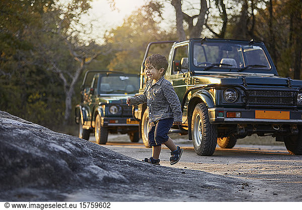 Little boy exploring nature  off road vehicles in background