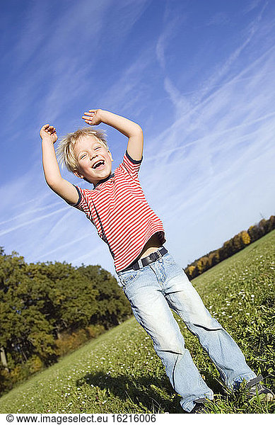 Little boy (4-5) fooling about in the meadow