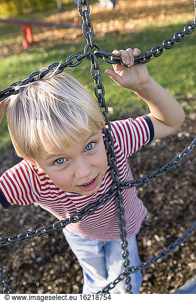 Little boy (4-5) holding metal monkey ropes  elevated view