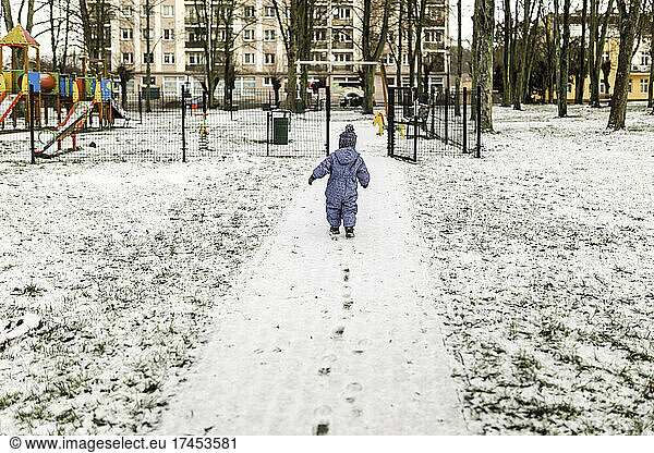 Little boy in blue onesie and warm hat going to playground