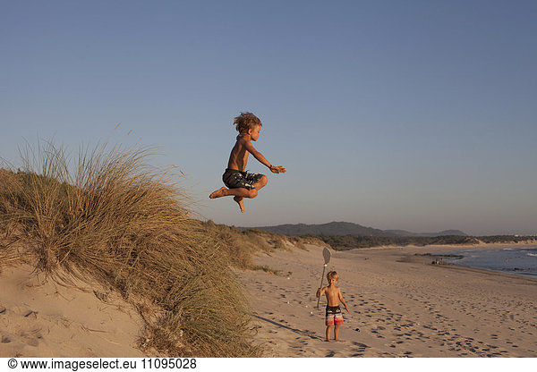 Little boy jumping from sand dune on the beach  Viana do Castelo  Norte Region  Portugal