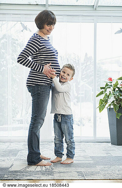 Little boy listening to pregnant mother's stomach