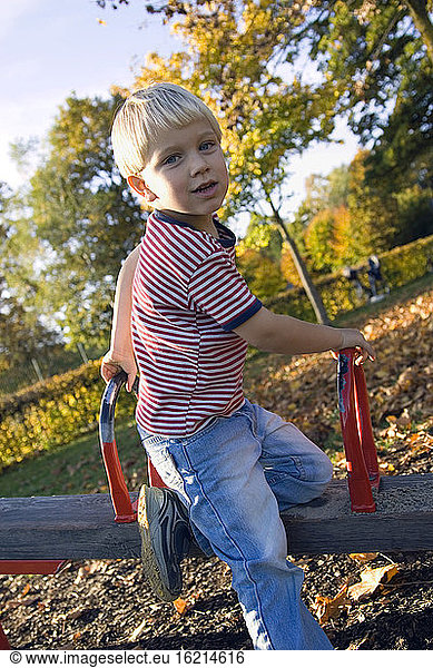 Little boy (4-5) playing on a swing