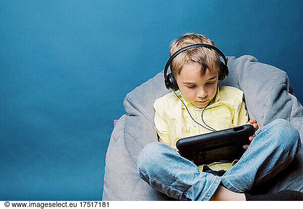 Little boy playing video games in bean bag at home