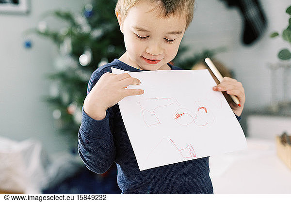 Little boy proudly showing off his drawing for Santa.