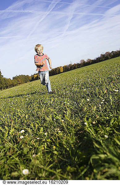 Little boy (4-5) running across meadow