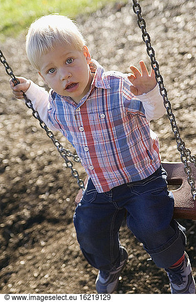 Little boy (2-3) sitting on swing