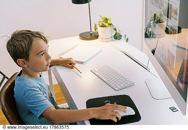 little boy using the computer to surf the web in his room